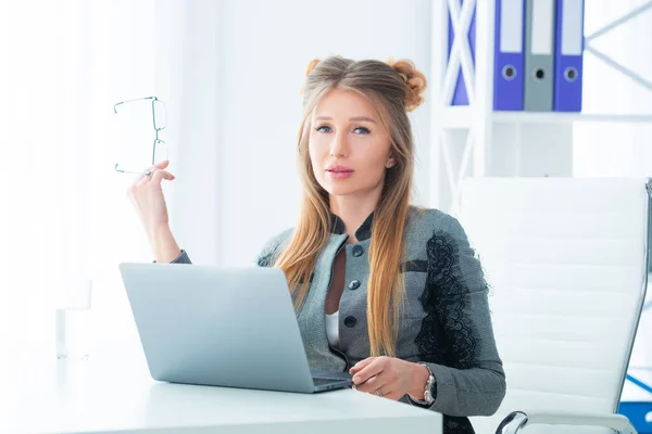 Affärskvinna i strikt kostym arbetar på ett kontor vid ett skrivbord på en bärbar dator — Stockfoto