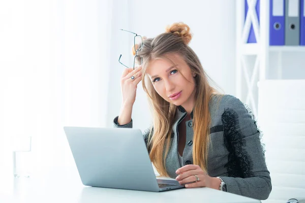 Business woman in a strict business suit works in an office at a desk on a laptop — Stock Photo, Image