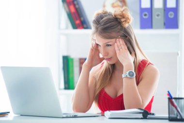 Kırmızı bluzlu genç bir kadın bilgisayar masasında bir ofiste oturuyor. Kadın işi..