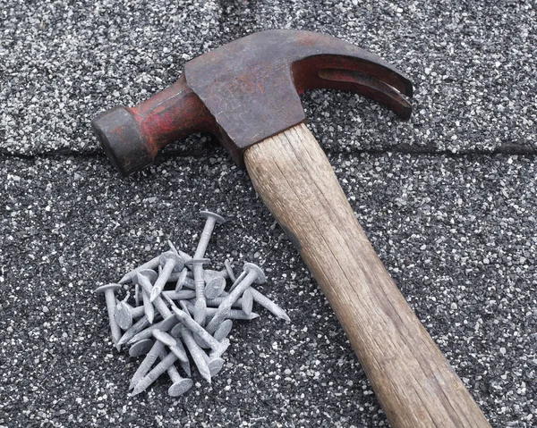 Hammer and galvanized roofing nails on shingles