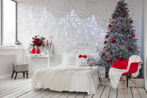 New Year\'s interior, a white photo studio with a silver Christmas tree and a white bed, red Christmas tree decorations and interior elements