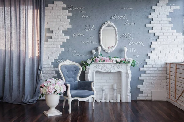 beyaz bir şömine ve gri bir vintage sandalye, gri bir oda dekore peonies ve güzel çiçekler ile; Duvarda bir yazı