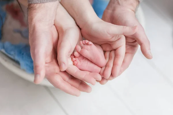 Yeni doğan bir çocuğun anne ve baba, veliler bir parçası beyaz arka plan üzerinde elinde elinde küçük bacakları