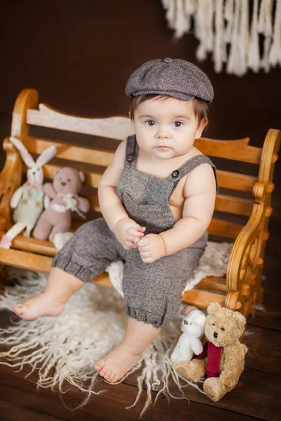 küçük çocuk bir kabadayı olarak giyinmiş, bir kap ile bir bahçe çocuk, kahverengi bir çikolata arka planda bir bankta oturur