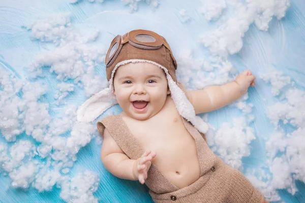 beyaz bulutlar, küçük bir pilot ile kahverengi mavi arka planda bir kahverengi pilot elbise küçük çocuk