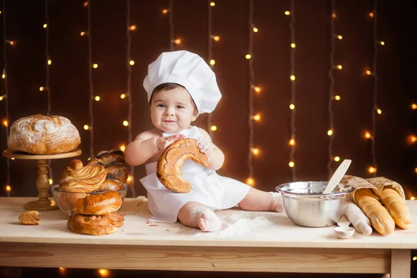 çörekler ve ekmek ile Şef kostüm küçük çocuk kahverengi arka planda masada oturuyor