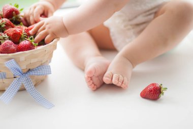 çilek sepeti yanında beyaz bir arka plan üzerinde bebek bacakları, berry ruh hali, bebek yaz