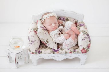 beyaz dantel bodysuit yeni doğan bebek kız bir akvaryumda bir japon balığı yanında bir vintage kanepede uyur, yeni doğan rüyalar, bebek hayatı, anne ebeveyn aşk, bebek gülümseme