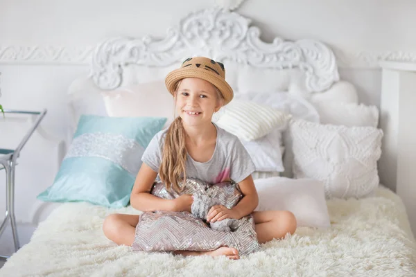 Uma Menina Chapéu Senta Uma Cama Quarto Branco Abraça Travesseiro — Fotografia de Stock