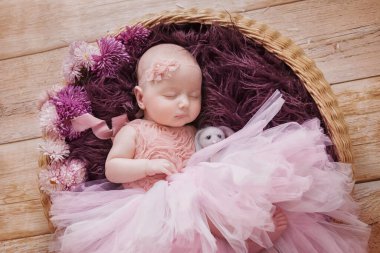 Pembe şapkalı küçük bebek bebek yumuşak peluş oyuncaklarıyla uyur turkuaz arka planda, battaniyeyle örtülü, yeni doğmuş fotoğraf çekimleriyle.