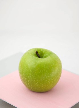 Pembe-gri arka planda olgun yeşil elma