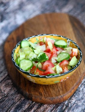 Domates salatası, salatalık, yeşillik, mango tahtasında el yapımı bir kasede maydanoz.