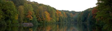Renkli ağaçlar ve ilk fenerlerle dolu sonbahar gölü panoramik manzarası