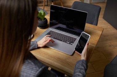 Yaşam tarzı eğitim öğrencisi. Businesswoman proje için laptop üzerinde çalışır. Millennial evde ofis içecek kahve defter üzerinde iş arıyor. Modern taşınabilir bilgisayar ve telefon kullanarak tanınmaz kadın