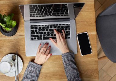 Düz yatıyordu. Businesswoman proje için laptop üzerinde çalışır. Millennial evde ofis içecek kahve defter üzerinde iş arıyor. Modern taşınabilir bilgisayar ve telefon kullanarak tanınmaz kadın