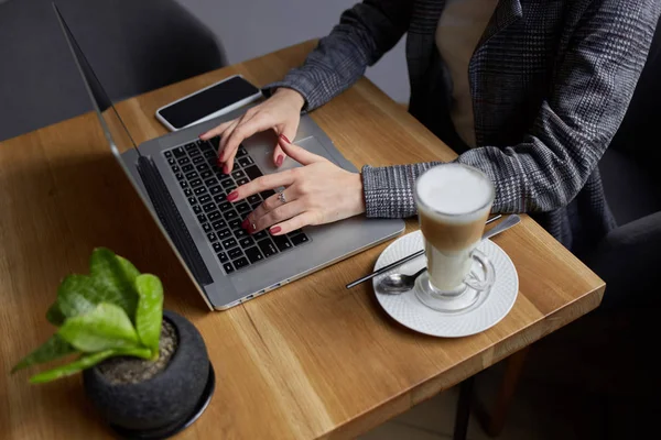 Yaşam tarzı eğitim öğrencisi. Businesswoman proje için laptop üzerinde çalışır. Millennial evde ofis içecek kahve defter üzerinde iş arıyor. Modern taşınabilir bilgisayar ve telefon kullanarak tanınmaz kadın