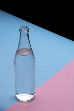 Parlak pembe ve mavi arka planda cam şişe su yakın