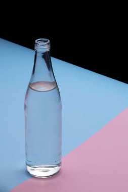 Parlak pembe ve mavi arka planda cam şişe su yakın