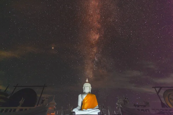 Samanyolu Galaksisi'nin yıldızlarının ışığı altında beyaz Buda görüntüsünün arkasında tahılla dolu bir gece. Görüntü Udonthani Wat Phutongtepnimit bazı tahıl veya gürültü ve yumuşak odak içerir, Tayland