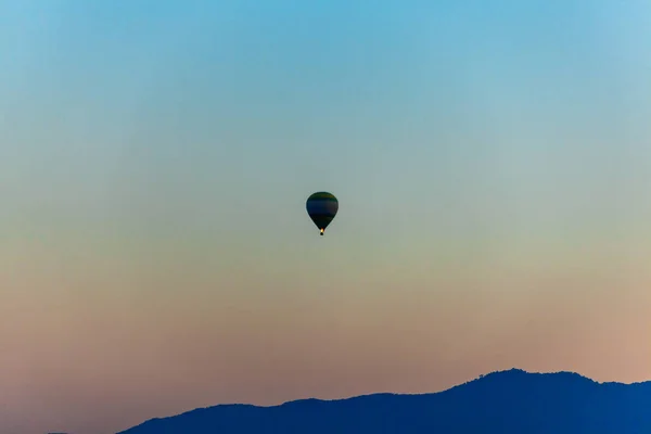 Sziluettje Színes Hőlégballon Repül Hegy Kék Égen Naplementekor — Stock Fotó