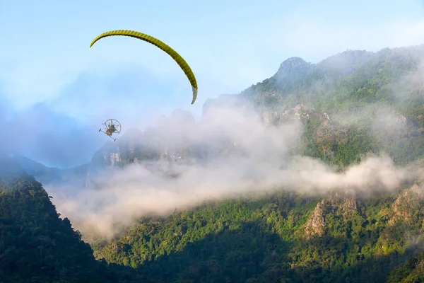 Paramotorlar güzel bir dağ manzarası üzerinde uçuyor ve Puslu ve mavi gökyüzü manzarası