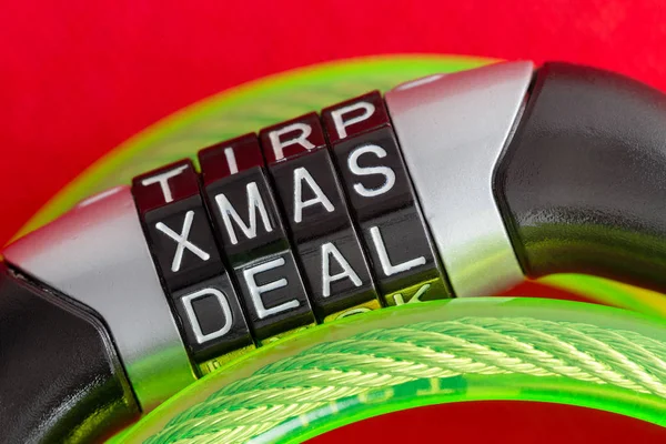 Letter combination bike lock with Xmas Deal code to unlock the steel security cable covered in green plastic over a festive red holiday background in a conceptual image