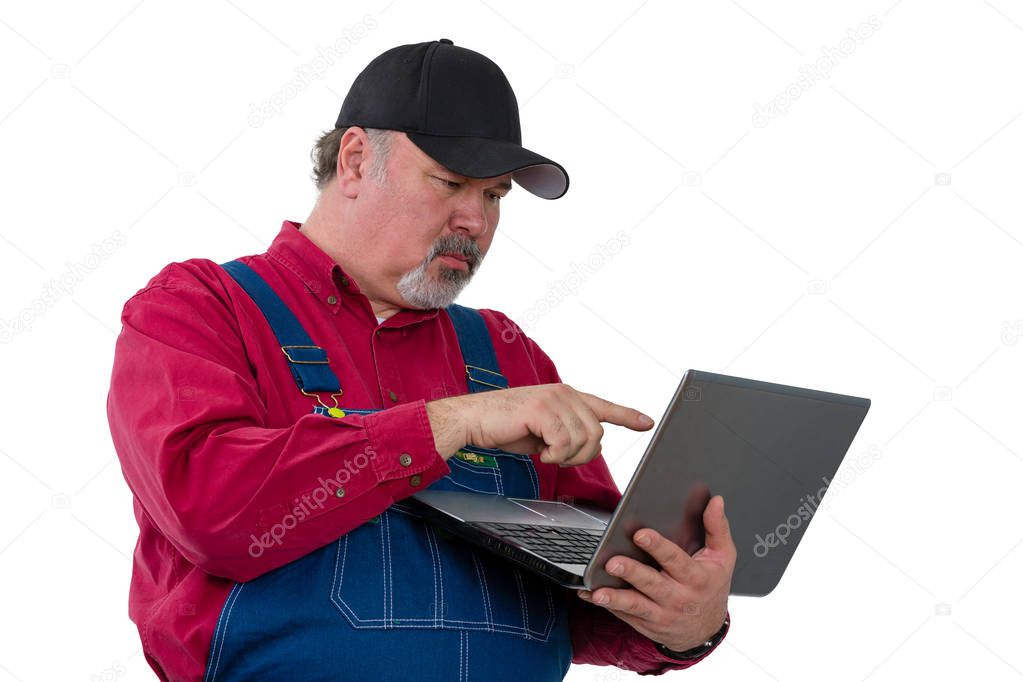 Adult male worker wearing dungarees using laptop while standing against white background