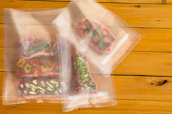 Multiple random meat dishes with bits of vegetables inside plastic bags sitting on wooden plank table