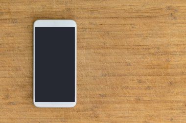 Tek dikdörtgen izole beyaz akıllı telefon kapalı oturma üstünde tepe-in tırmalamak ahşap masa yüzeyi ile