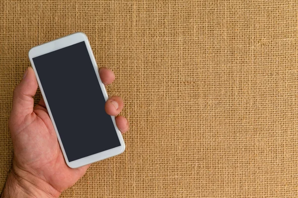 Man Holding Smart Phone Burlap Background Wit Copy Space Right — Stock Photo, Image