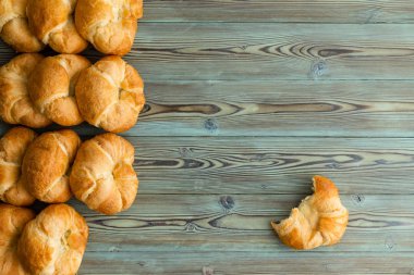 Tek bir buçuk ile yan sınır taze pişmiş kruvasanlar satırlarının rustik ahşap kopya alanı ile lekeli kruvasan tarafa yenen