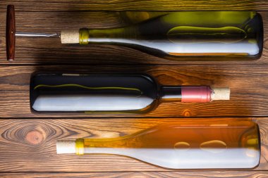 Yüksek açılı görünüş karşı ahşap arka plan yalan üç şarap şişe