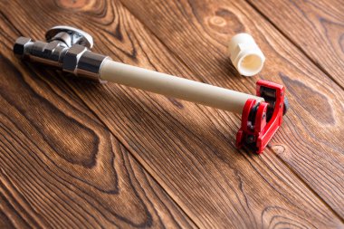 Bir su tesisatı kurulması ya da tamiri kopya alanı ile ahşap bir masa üzerinde bir parlak kırmızı boru kesici içinde için plastik Cpvc boru uzunluğu