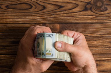 Adam 100 dolar faturaları bunlar aracılığıyla üzerinde bir rustik ahşap masa kopya alanı ile thumbing kalın bir yığın denetimi