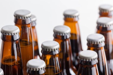 Düşük açılı sığ dof görünümünü boyunlu ve zanaat bira beyaz bir arka plan satırlarda düzenlenen tam kahverengi şişe kapakları