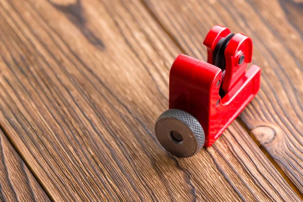 关闭一个红色的钢管切割机在质朴的木材与复制空间查看高角度显示车轮切割管道管道或管道 — 图库照片