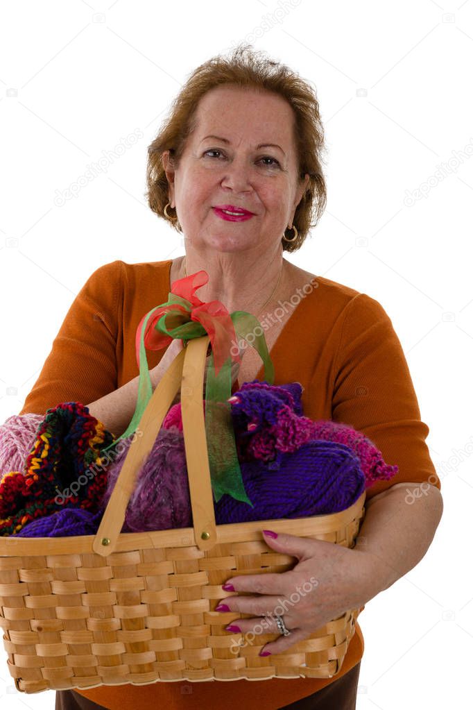 Portrait of cheerful senior woman holding basket with colourful yarn