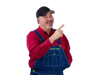 Mavi üniforma tulum, kırmızı gömlek ve Kupası beyaz zemin üzerine izole kopya alanı, ayakta, onun parmak ile işaret orta yaşlı erkek işçi. Kameraya bakarak ve gülümseyen