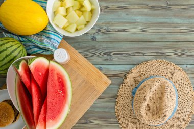 Taze sulu karpuz ve kanarya kavun bir yaz piknik masa üzerinde kopya alanı ile yukarıdan izlendi rustik bir saman sunhat ile dilimlenmiş