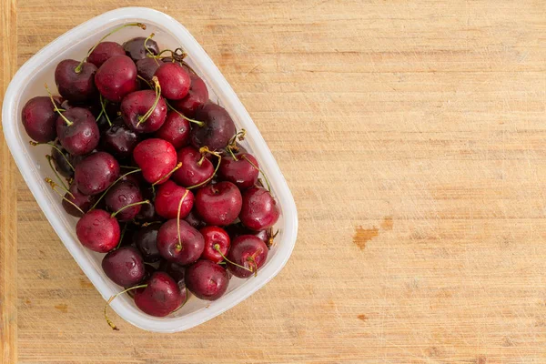 Small Plastic Container Filled Red Cherries Placed Side Old Bamboo — Stock Photo, Image