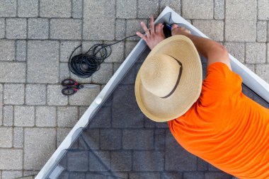 Bozuk tel ağ üzerinde bir dış veranda kaldırım yatan bir ekran kapı yerine adam ona diz çökmüş aşağı bakıyor yukarıdan izlendi