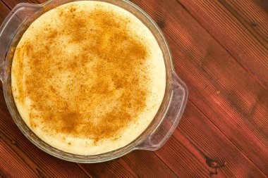 Yuvarlak cam güveç genel gider görünümünü sütlaç ile çanak ve tarçın bir redwood piknik masada yer ile kaplı