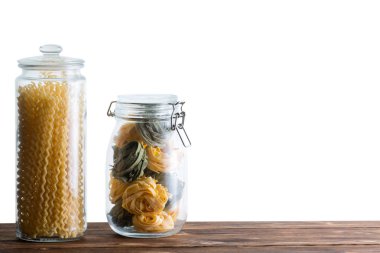 Ev yapımı fettuccine ve düdük bucati lunghi uzun spiraller kopya alanı ile beyaz bir arka plan ile taze kurutulmuş makarna iki depolama kavanozlar dolu