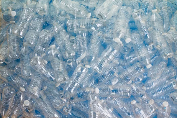 Jumble of clean empty plastic pet bottles on a blue background ready for recycling to save the planet in a full frame background