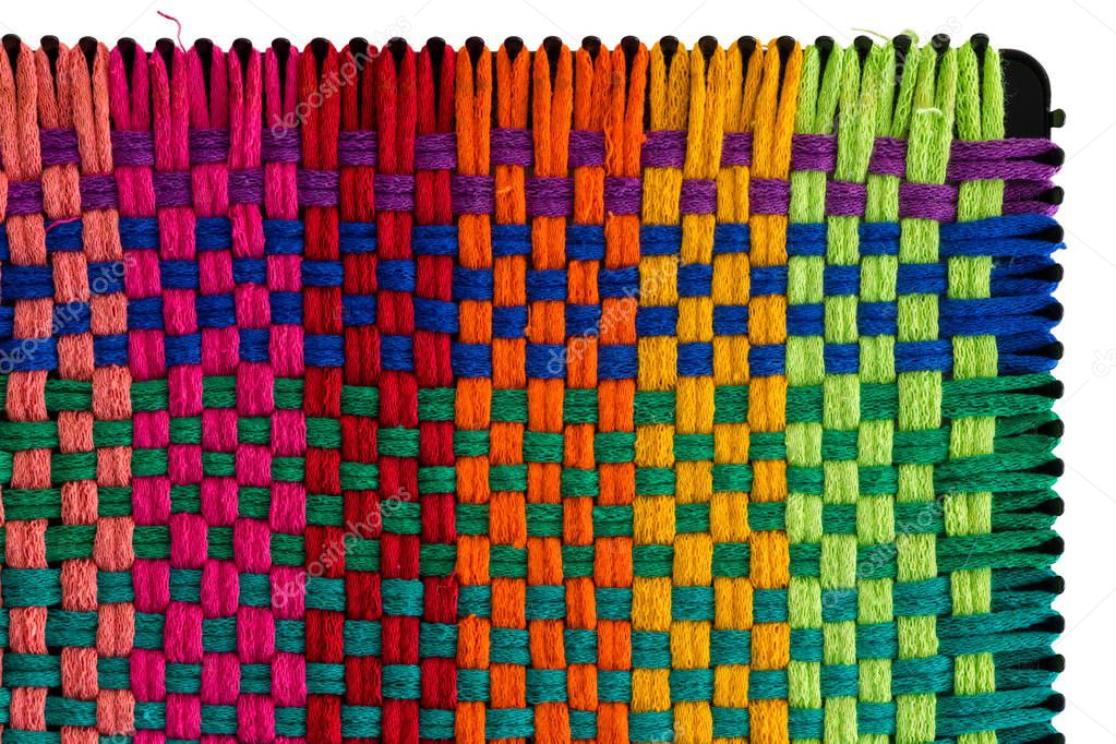 Close up on top right corner of plastic weaving guide with rainbow colored threads interwoven in rows