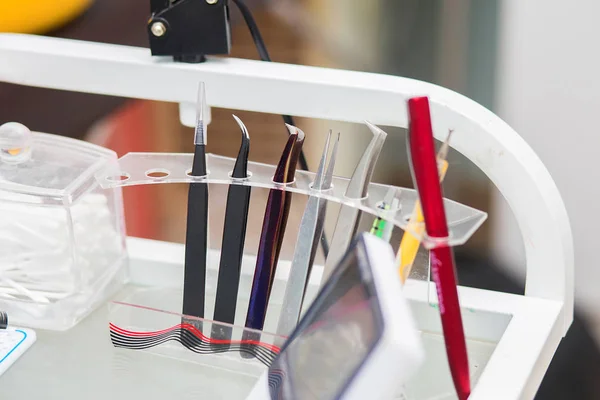 Tools of the master in eyelash extension stand in a support on a desktop, in beauty shop