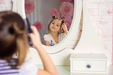 Kız beyaz odada ayna önünde oturan saç fırçaları.