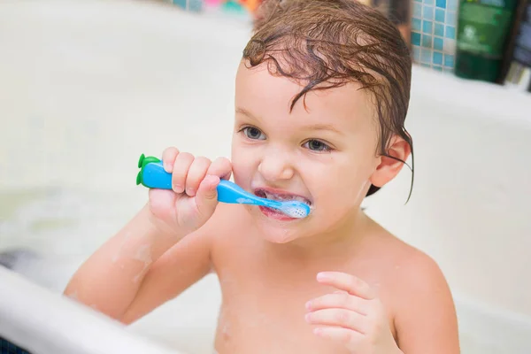 Küçük çocuk banyoda oturur ve kendi kendini diş mavi bir fırça — Stok fotoğraf