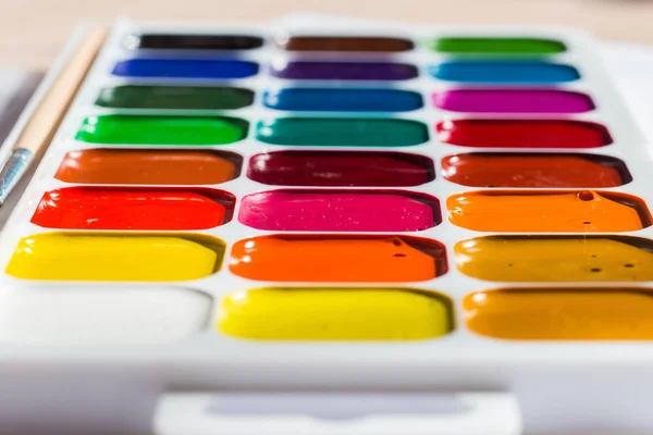 Різнокольорові яскраві акварельні фарби на столі крупним планом — стокове фото