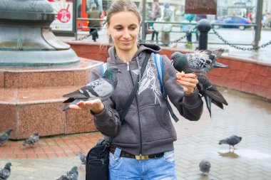 Genç kız turist şehir meydanında ellerini güvercinleri besler
